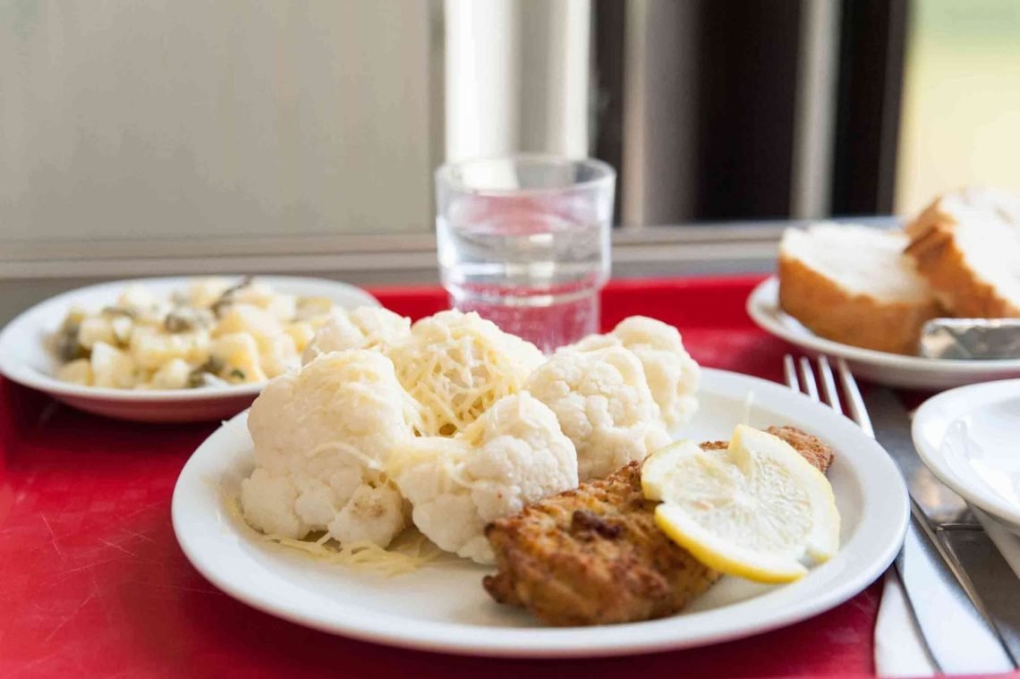 French school lunch tray with baked fish, cauliflower, and a slice of lemon