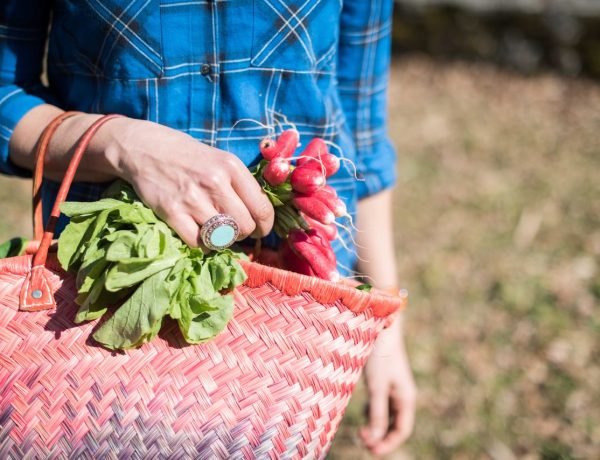 French woman walking with straw shopping basket full of radishes