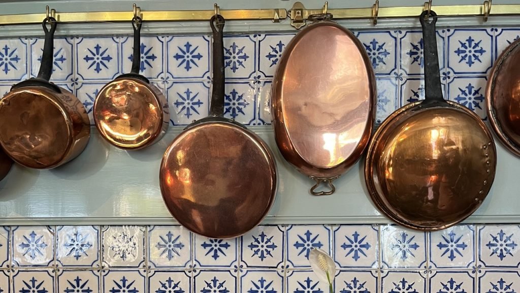 Traditional French copper pots hanging in a kitchen — illustrating simple, real-food cooking in the French wellbeing lifestyle.