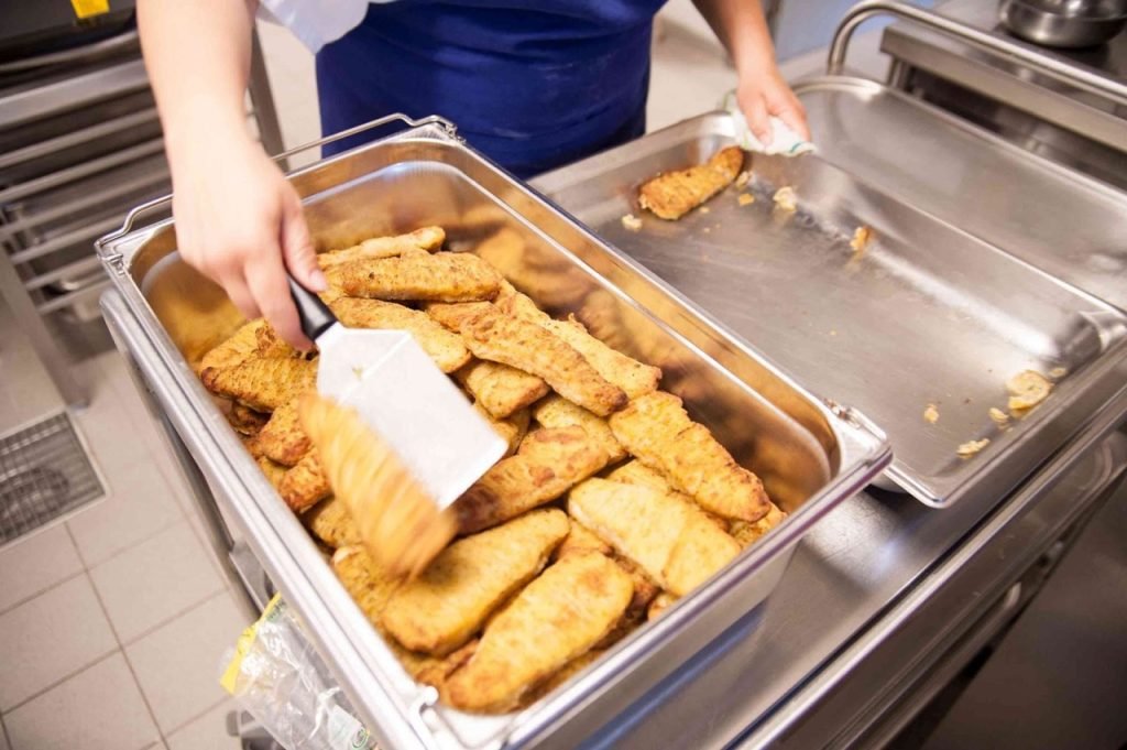 Baked fish being prepared to serve for French school lunch.