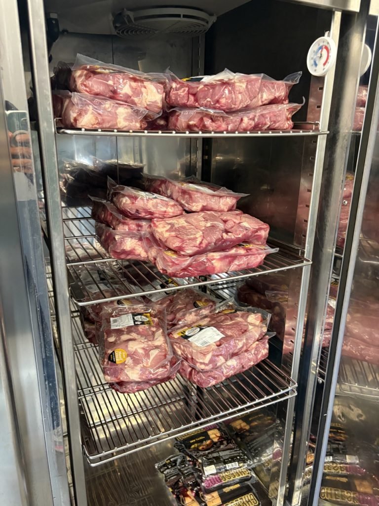 Packed meet inside refrigerator of French school cafeteria kitchen.