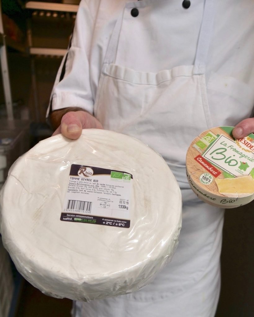 Selection of organic cheeses inside pantry of French school cafeteria kitchen.