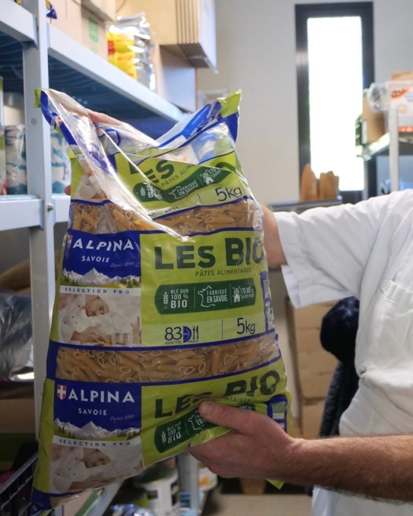 Large bag of local and organic pasta inside pantry of French school cafeteria kitchen.