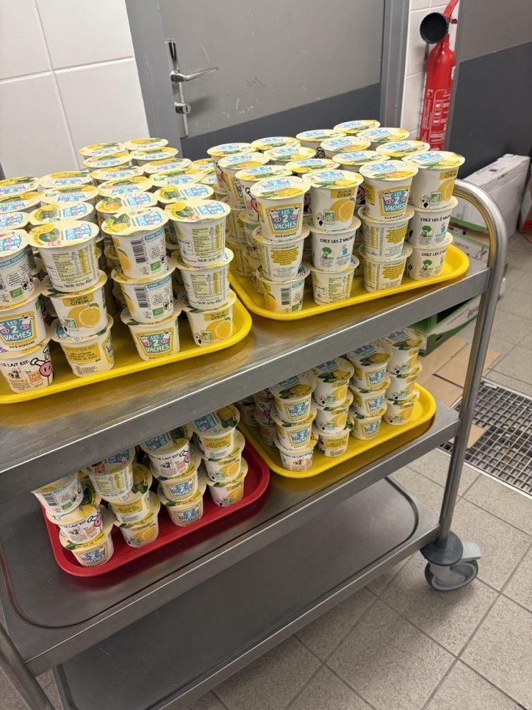 Organic yogurts on a large serving chariot inside French school cafeteria kitchen.