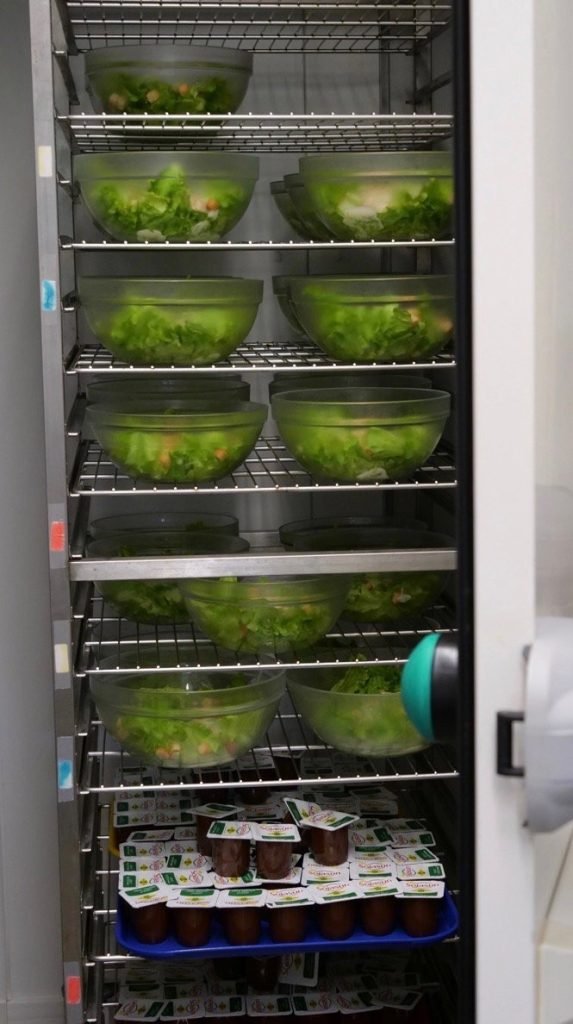 Salad bowls and chocolate yogurts prepared for French school lunch.