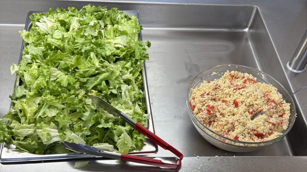 Taboule next to a tray of fresh green salad at a French school self-serve lunch station.