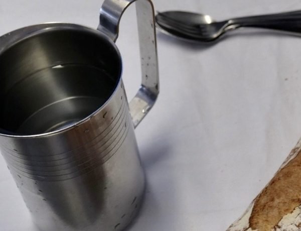 Metal water jug on a table in a French school lunchroom, showing how children drink water with every meal.