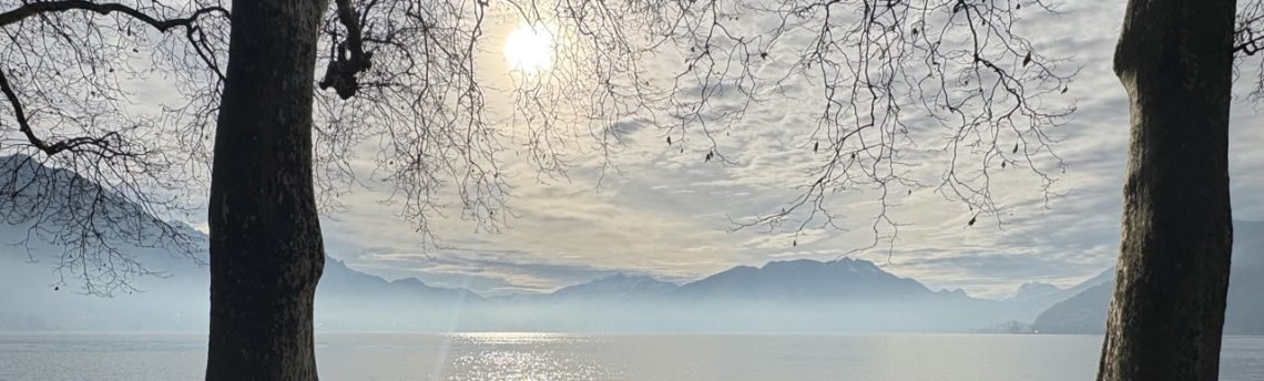 A calm lakeside view of Annecy, France, reflecting the simple French wellbeing at the heart of this site.