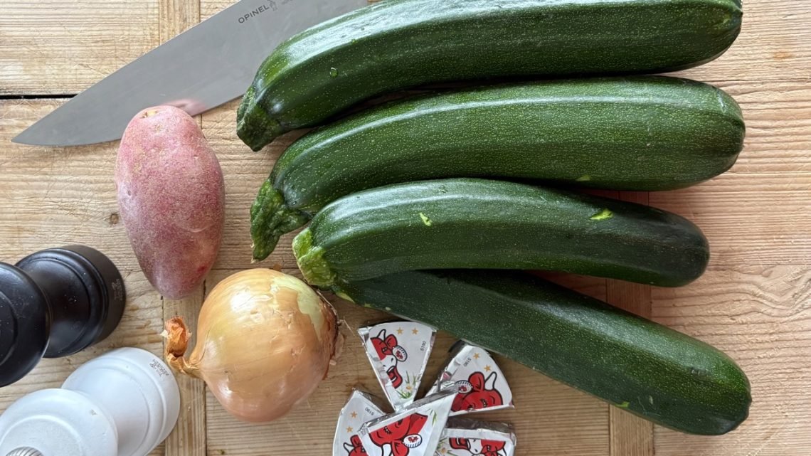 Chopped zucchini and vegetables on a wooden board with an Opinel knife, prepared for a French school lunch style zucchini soup
