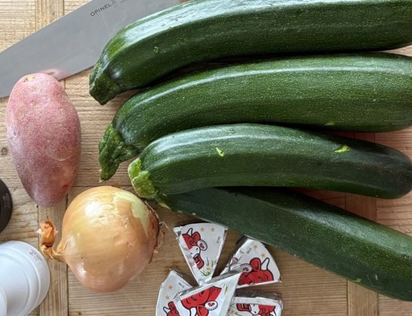 Chopped zucchini and vegetables on a wooden board with an Opinel knife, prepared for a French school lunch style zucchini soup
