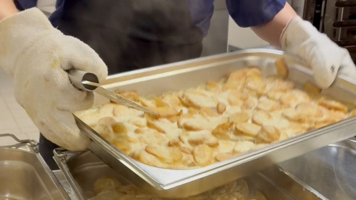 Kitchen staff with steaming platter of potato gratin