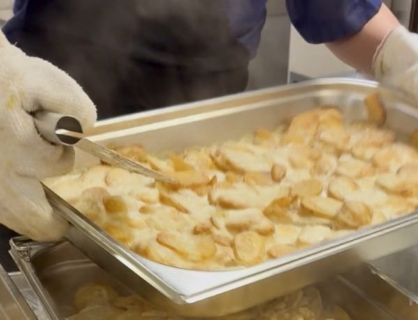 Kitchen staff with steaming platter of potato gratin