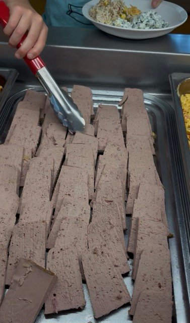 Student choosing pate for French school lunch